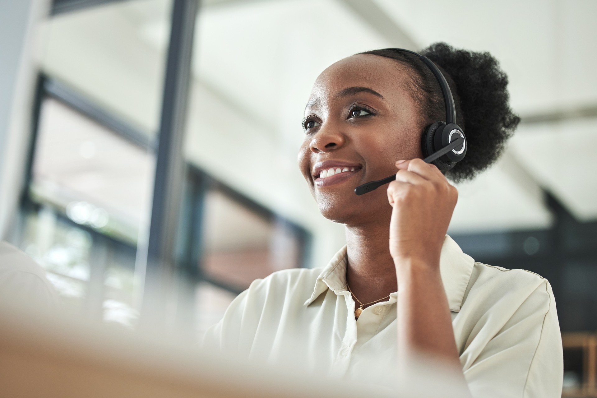 Low angle shot of an attractive young call centre agent sitting alone in the office and using her computer